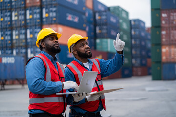 Two African engineers Supervising loading containers from cargo ships. logistics yard business...