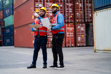 Fototapeta premium Two African engineers Supervising loading containers from cargo ships. logistics yard business Import and Export Freight Forwarding Industry