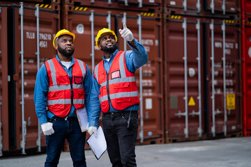 Two African engineers Supervising loading containers from cargo ships. logistics yard business...