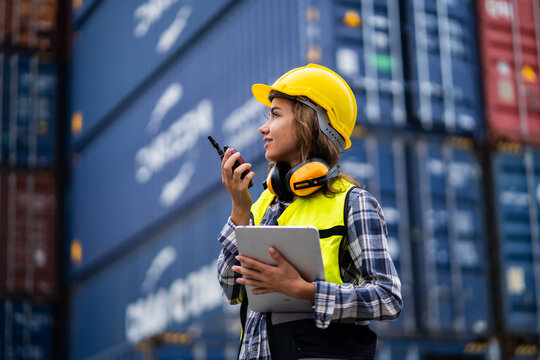 Female workers in the container industry transporting imports and exports of goods to the shipping business. Confident engineer in container terminal.