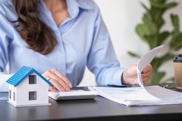 Asian woman with long hair in the blue shirt is using a credit card for buying a new house and looking at home-buying documents The idea of purchasing a home with a credit card.