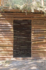 one brown wooden empty open gazebo made of pine logs among the trees in the park