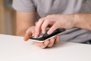 A man cleans the phone screen to stick a protective tempered glass. Broken protective glass