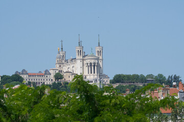Fototapeta na wymiar Basilica our lady of Fourvière in Lyon, France at the top of the fourvière hill with many trees in the foreground.