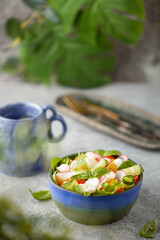 Salad with mozzarella and vegetables in homemade bowl on the table.
