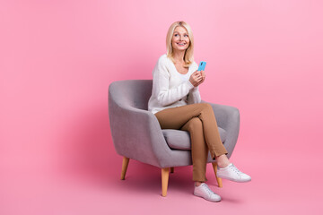 Obraz na płótnie Canvas Full size portrait of nice positive person sit comfort chair use smart phone look empty space isolated on pink color background