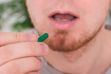 Obraz premium A young man takes out a tablet, a pill from a blister pack. The concept of health, medicine.