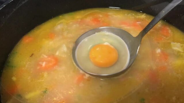 Preparing the traditional "chicken soup" with egg in 4K video