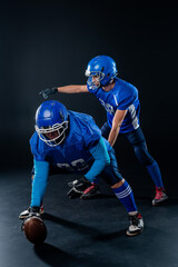 Two American football players are ready to start the game on a black background. 