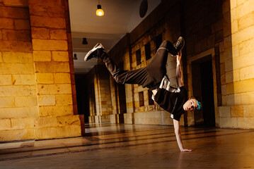 white teenage boy breakdancing in the arcade of an old building. b-boy. youth culture.
