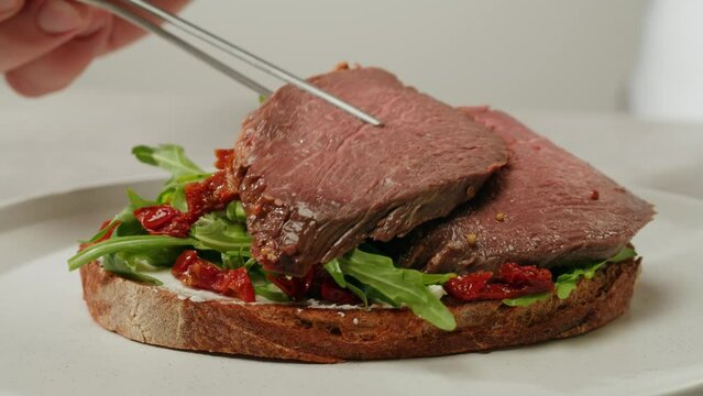 American pastrami sandwich in New York ham meet cuts. chef cooking Famous thick cut sous vide beef sandwich on restaurant cafe kitchen.