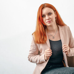 Portrait of a red-haired woman in a light jacket on a white background