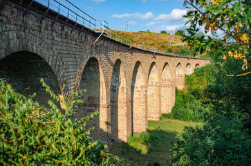 Fototapeta na wymiar Ancient stone railway arch bridge over the valley