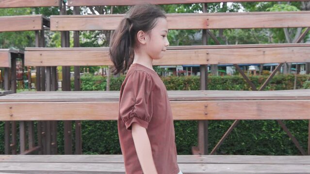 Side view of one adorable asian elementary girl who walking along the beautiful way outdoor to school or go back home shows concept of childhood education for gaining knowledge.