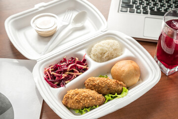 Meatball bento in the plastic box with the ultrabook on background. Busy lunch