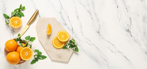 Bowl, cutting board and knife with fresh oranges on light background with space for text