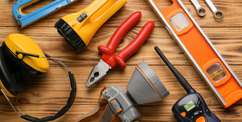Construction tools with safety headphones and flashlights on wooden background