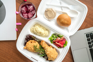 Meatball bento in the plastic box with the ultrabook on background. Busy lunch
