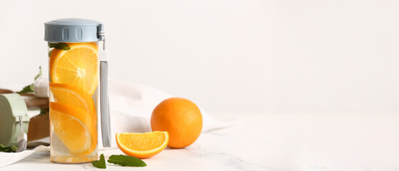 Bottle of orange infused water on light background with space for text