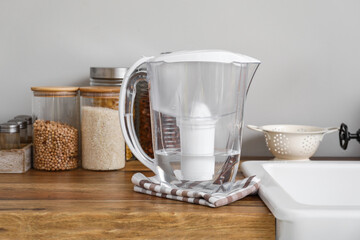 Water filter jug with napkin on kitchen counter near light wall