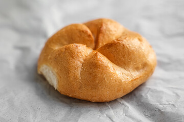 Kaiser roll on white paper, closeup