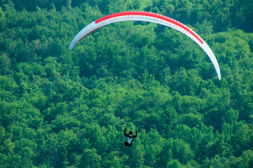 Paraglider flies in the air. Aerial view of paragliding. Paraglider flies above the mountains in a...