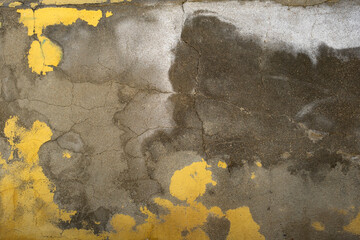 Old cracked concrete wall with worn out yellow paint