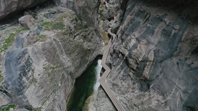 Aerial view of a woman standing on an elevated walkway between two giant rocky walls, Parrizal de Beceite, Rio, Spain.