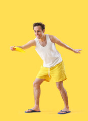 Fototapeta na wymiar Happy young man playing frisbee on yellow background