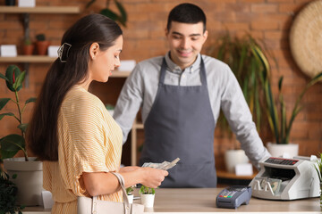 Young woman with dollar banknotes in flower shop