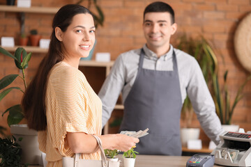 Young woman with dollar banknotes in flower shop