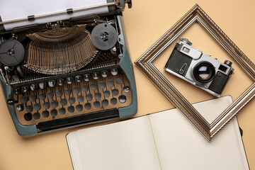 Composition with vintage typewriter, photo camera and opened notebook on beige background