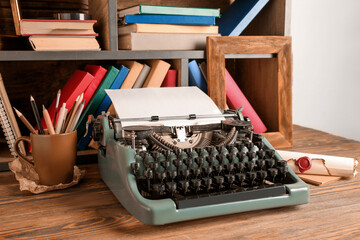 Vintage typewriter on wooden table near shelves with books