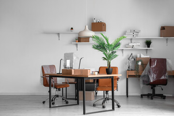 Interior of office with workplaces and cardboard boxes on moving day