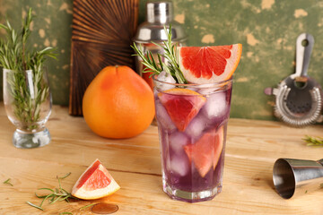 Glass of purple gin and tonic with grapefruits on wooden table