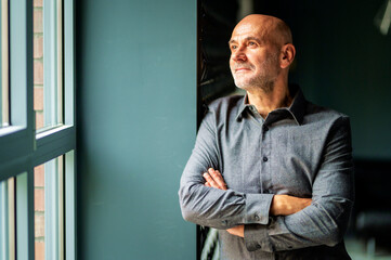Portrait of thinking business man standing with arms crossed at the office