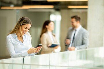 Young business woman with mobile phone in the office hallway