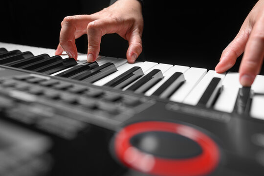 Playing a synthesizer on a dark background. The musician plays the synthesizer.