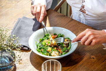 Close-up lifestyle girl in restaurant eat salad with greens, vegetables, balsamic sauce, on terrace, hands in picture. Healthy lunch, food delivery, cafe menu. Break for energy, vitamins, refreshness