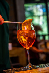 Realistic photo, close-up view of professional bartender in bar making cocktail in a tall glass, with ice and alcohol, male hands in picture