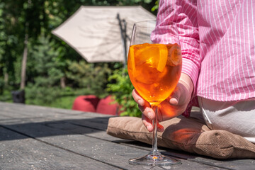 Girl drink iced alcohol Aperol spritz cocktail on summer terrace, in cafe or restaurant