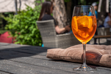 Girl drink iced alcohol Aperol spritz cocktail on summer terrace, in cafe or restaurant