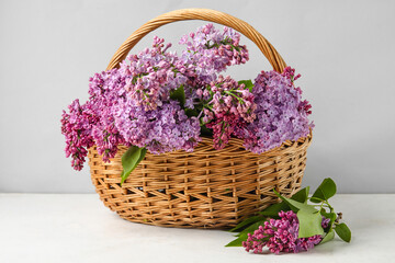 Fototapeta na wymiar Wicker basket with aromatic lilac flowers on light table