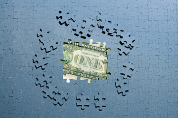 dollar inflation, hiding income concept, dollar bill hidden under unfinished puzzles