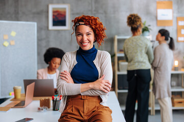 Young female executive sitting on office desk
