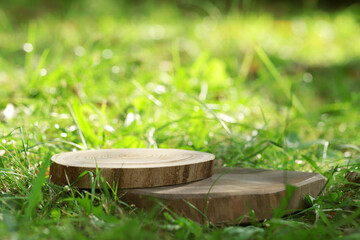 A podium made of sawn wood with a natural background on the grass. Front showcase with a stand for the presentation of goods. With a beautiful view of juicy greenery with bokeh.