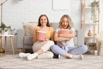 Young sisters eating popcorn at home