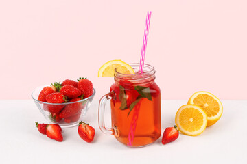 Mason jar of tasty strawberry drink with fresh berries and lemon on white background
