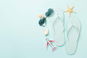 Flip flops with sunglasses and airplane on color background, top view - obrazy, fototapety, plakaty