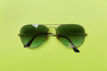 Sunglasses on color background, top view.